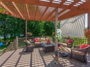 Outdoor seating with festoon lights on pergola, floral cushions, and scenic garden view.