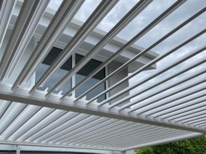 Modern white pergola structure attached to a house, highlighting outdoor shade options and pergola permit considerations.