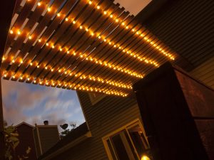 Wooden pergola with string lights, showcasing the best pergola material for creating a cosy backyard atmosphere.