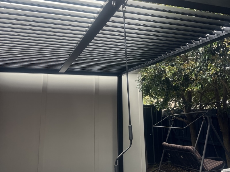 Corner Pergola Designs shown with louvre pergola beside garden swing in shaded corner area.