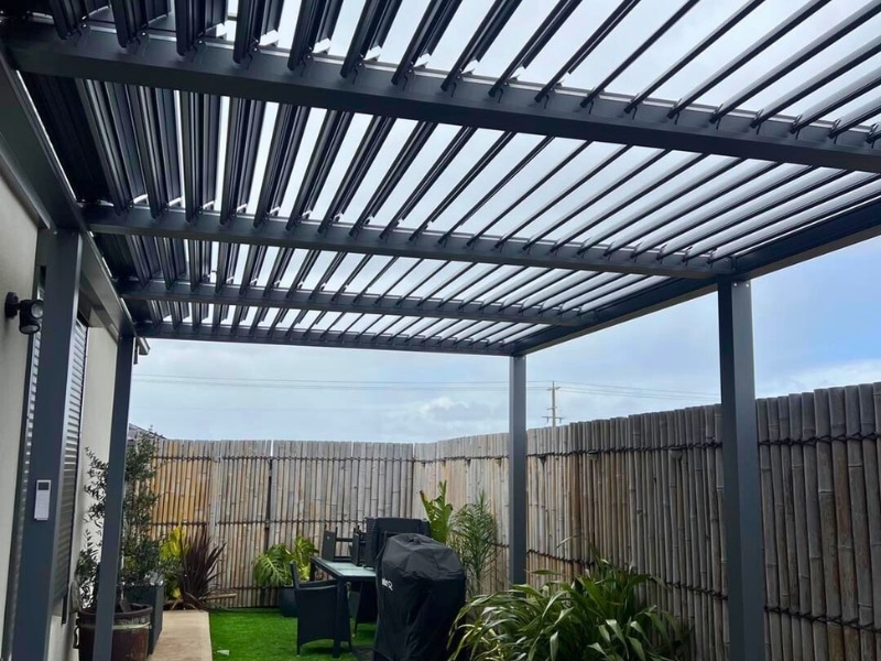Vines On Pergola shown with modern louvre pergola over garden deck surrounded by greenery.