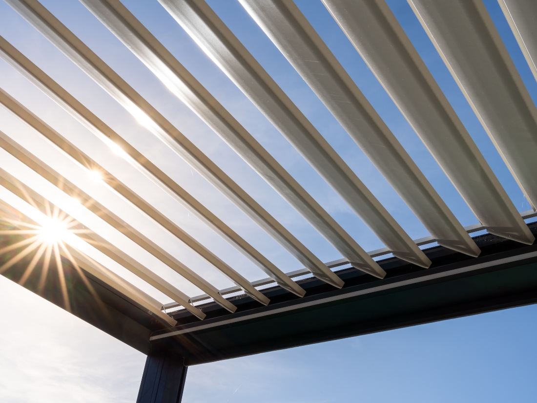 Close-up of an open pergola with adjustable louvered roof, allowing sunlight control for outdoor comfort.