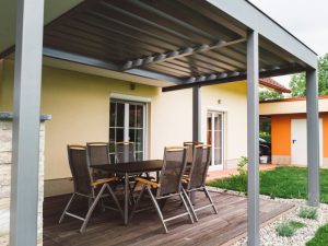 Outdoor dining area under a metal pergola with signs of a sagging pergola structure affecting stability and aesthetics.