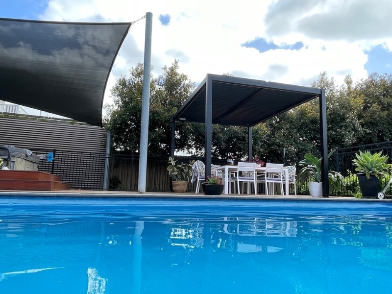 Best Season for Pergola shown with poolside motorised pergola shading outdoor dining area in sunny weather.