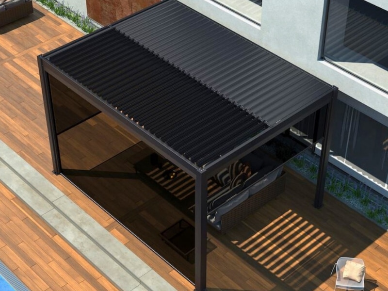 Modern pergola in winter shown with closed louvre roof over outdoor seating beside pool.