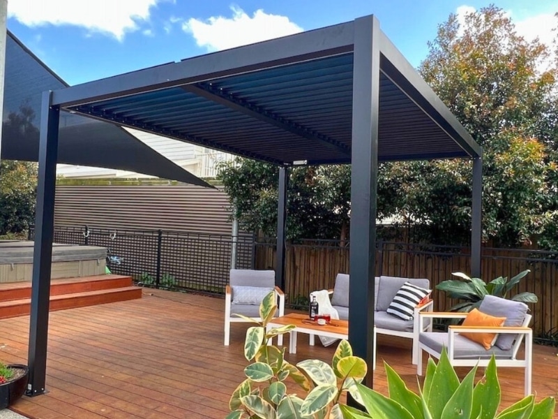 Pergola sizes shown with a medium black pergola covering outdoor seating on a timber deck.
