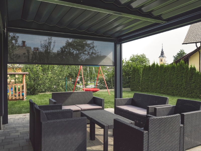 Corner pergola with sides used as lounge space with garden view and child’s play area.
