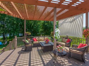 pergola design in balcony with timber frame, wicker furniture, privacy screen, and floral accents on upper deck
