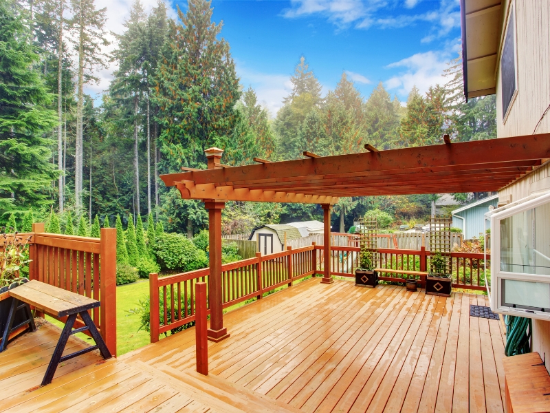 open pergola design in balcony with exposed timber beams on upper-level deck surrounded by trees and fencing