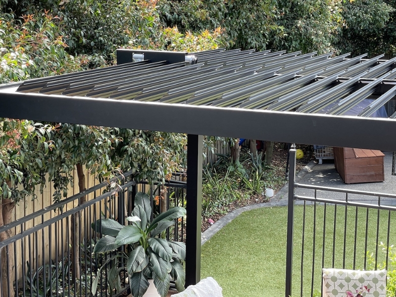 Backyard view of black metal pergola with standard pergola dimensions.
