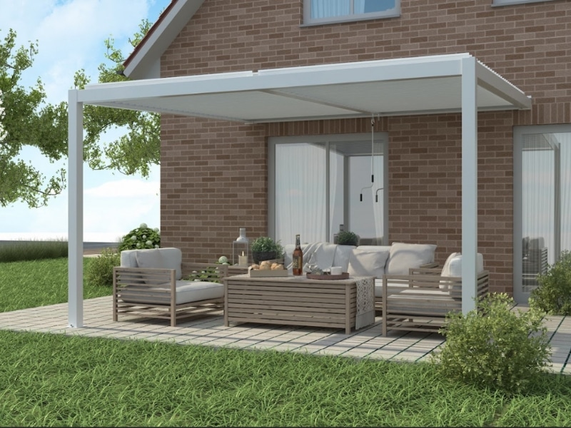 White wall pergola kits attached to brick house shading outdoor lounge setting.