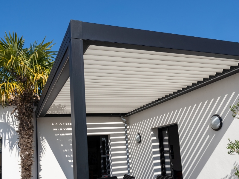 Portable pergola kits with white aluminium louvres creating dynamic shadows on a rendered home exterior