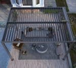 Top view of black motorised louvered pergola with outdoor furniture, offering automated shade for elegant poolside living.