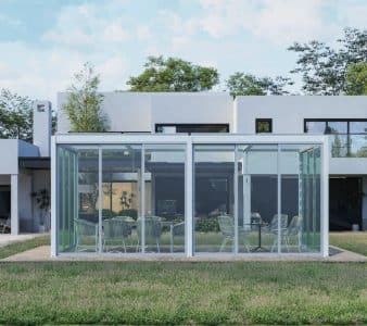 Glass-enclosed patio structure with modern furniture, serving as functional and elegant home add ons for outdoor spaces.