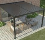 Wall mounted manual louvered pergola in black, attached to brick home with outdoor lounge setting on paved patio.