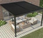 Aerial view of a stylish louvered pergola mounted to a brick wall, covering an outdoor seating area with wooden and striped cushions on tiled flooring.