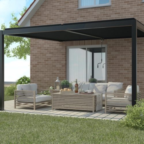 Modern wall-mounted manual louvered pergola with sleek black frame over a cozy outdoor lounge area featuring light wooden furniture and a brick house backdrop.
