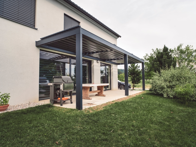 Attached garden pergola designs with flat louvred roof shading concrete patio space.