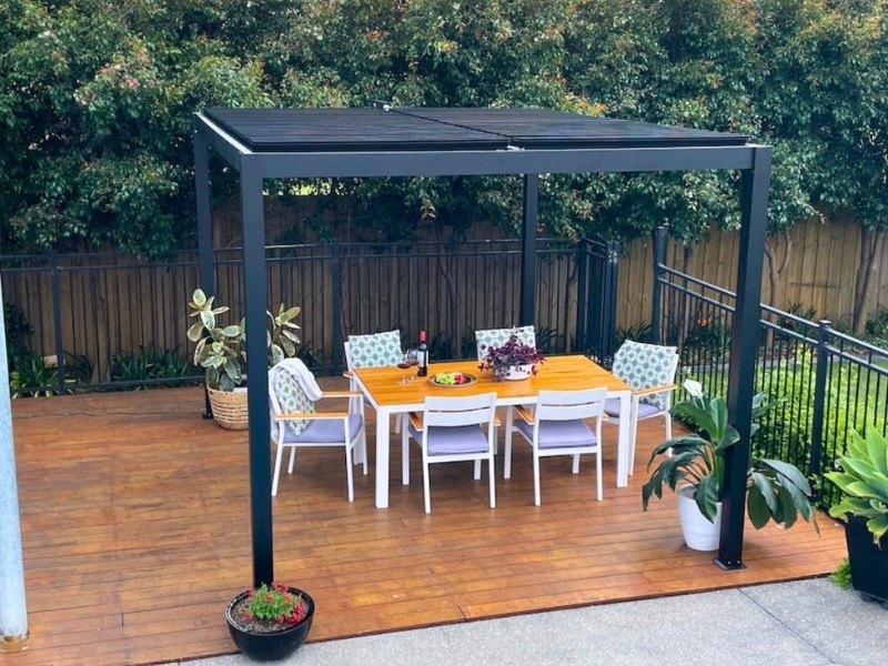 Pergolas on patios shading outdoor dining table on timber deck with plants.