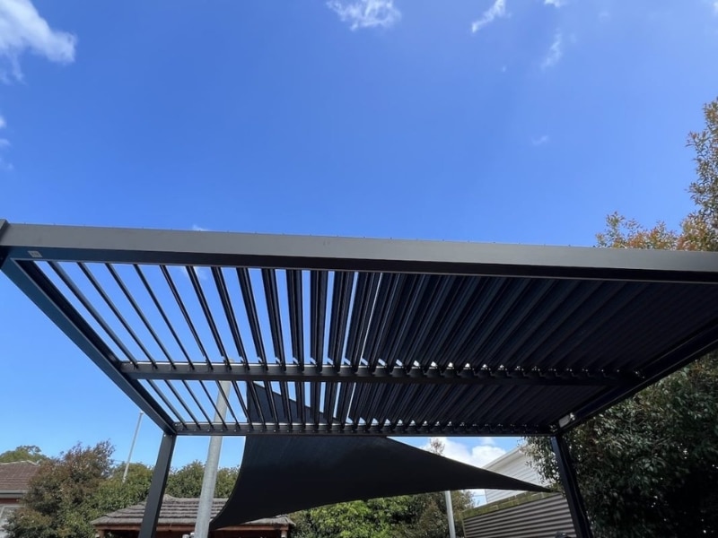Pergolas in Garden with adjustable louvre roof providing shade under clear sky.