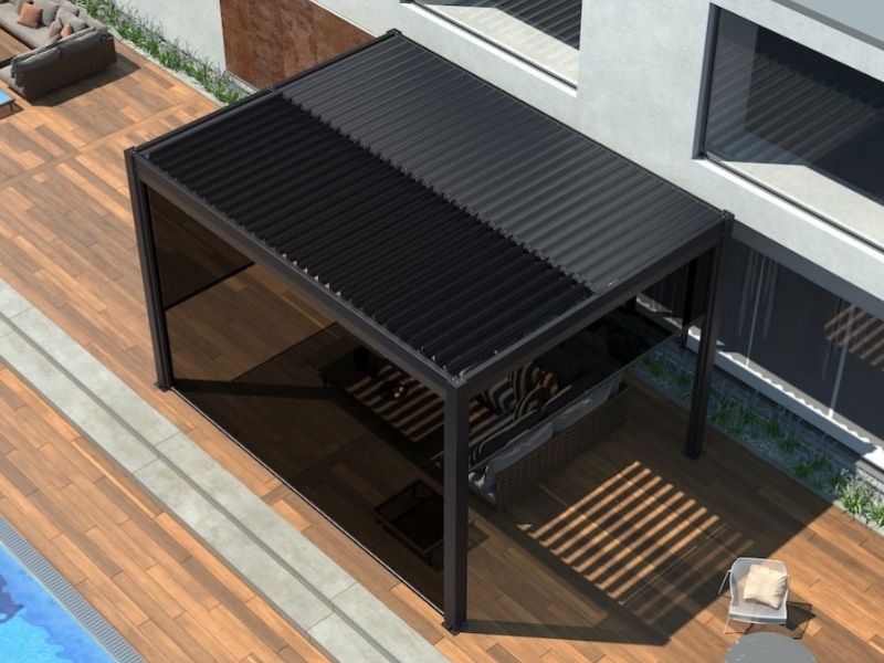 Pergola in front of house with black louvre roof beside pool and outdoor seating.