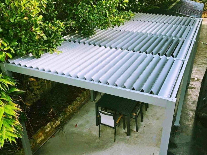 Aluminium pergola covering outdoor dining area, showcasing effective pergola layout planning in a leafy backyard.