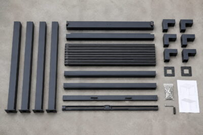 Aluminium pergola kit components laid out on a driveway before assembly