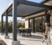 Installer securing an aluminium pergola to concrete footings and a brick house